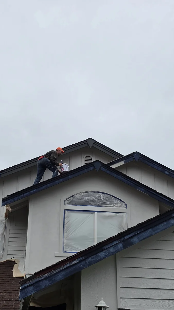 Painter working on upper trim and exterior details